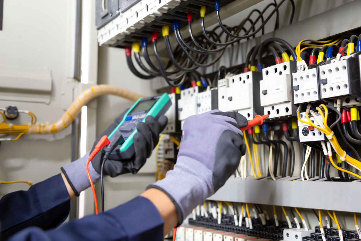 Image of an electrical engineer testing an installation of wires and relays in a commercial installation.